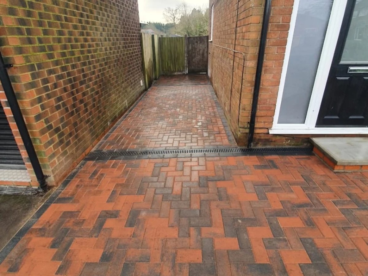 Completed block paved footpath with drainage channel between houses