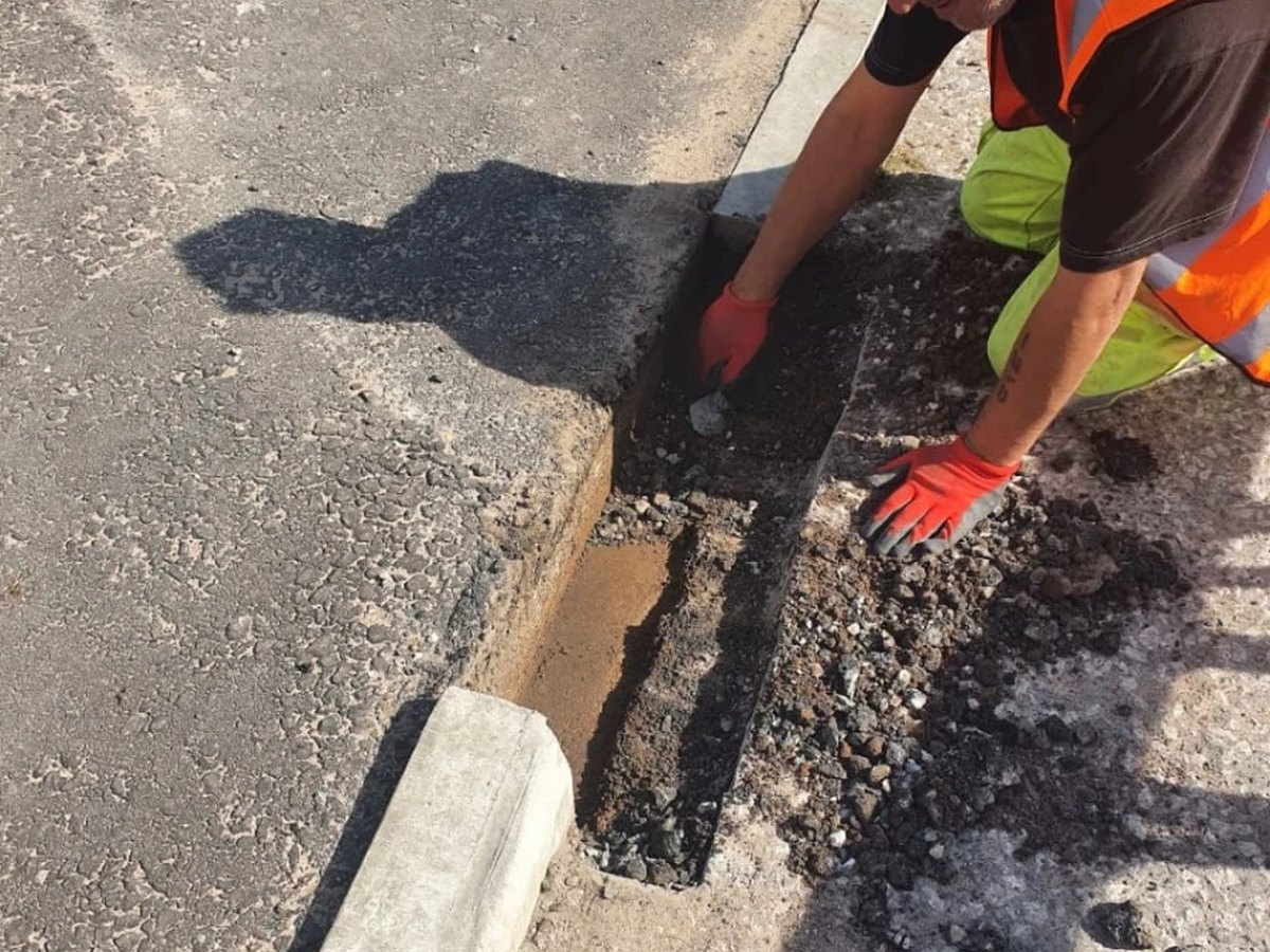 Foster operative bedding a concrete kerb and channel into a road edge
