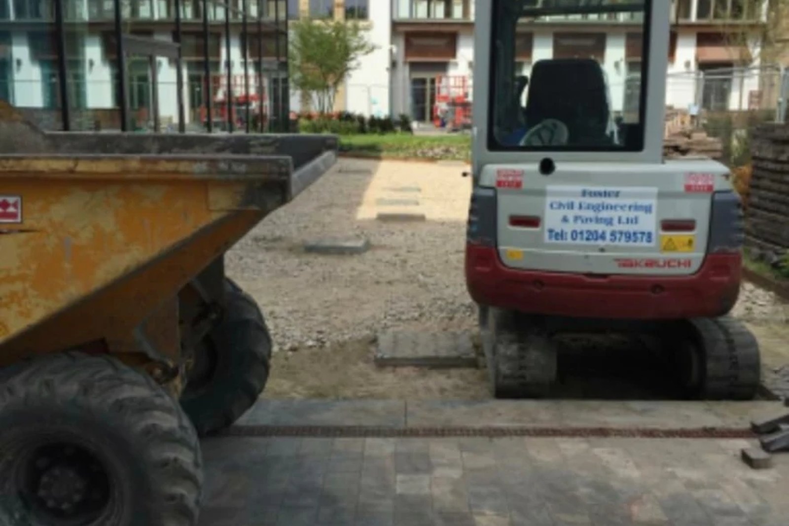 Foster mini excavator standing on newly laid granite sett paving beside the cathedral